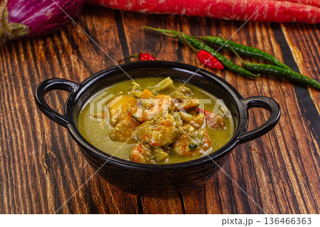 Thai green curry with shrimp and broccoli in a bowl, surrounded by fresh ingredients on a wooden table Thai green curry with shrimp and broccoli in a bowl, surrounded by fresh ingredients on a wooden table 136466363
