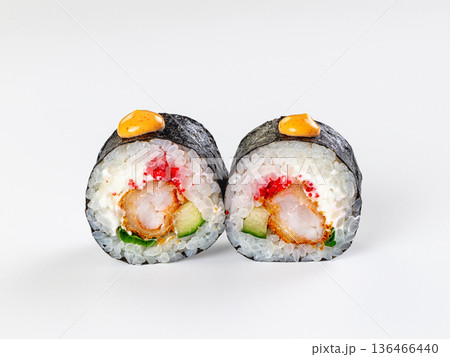 Two ebi tempura sushi rolls with tobiko, cucumber, and sauce isolated on a white background. Two ebi tempura sushi rolls with tobiko, cucumber, and sauce isolated on a white background. 136466440