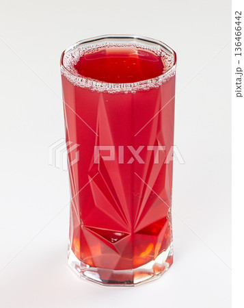 Vibrant red berry drink in a faceted glass tumbler, isolated on a clean white background. 136466442