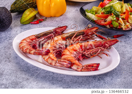 Grilled giant red prawns in a pan with fresh avocado, bell pepper, and salad on a stone table 136466532