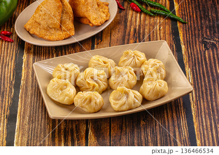 Plate of traditional steamed dumplings Momo on a table. Asian cuisine concept. Plate of traditional steamed dumplings Momo on a table. Asian cuisine concept. 136466534