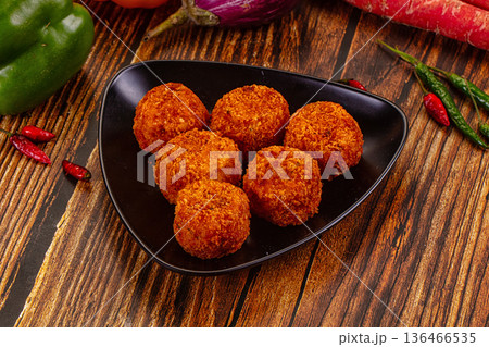 Golden fried cheese and vegetable balls, appetizer dish with fresh chili, peppers, and carrots on a wood table. Golden fried cheese and vegetable balls, appetizer dish with fresh chili, peppers, and carrots on a wood table. 136466535