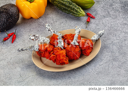 Spicy Indian Chicken Lollipops appetizer in a bowl with fresh vegetables 136466666