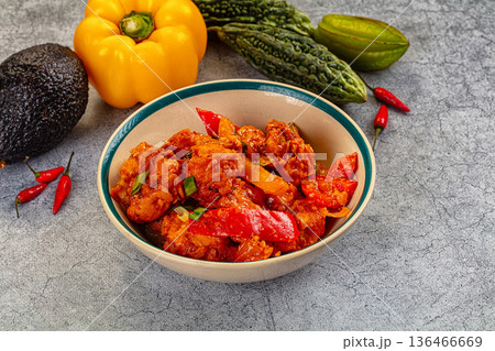 Spicy chicken curry in a bowl surrounded by fresh bell pepper, avocado, and bitter melon 136466669