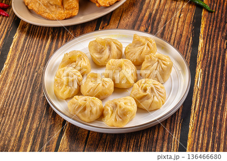 Plate of traditional steamed dumplings Momo on a table. Asian cuisine concept. 136466680