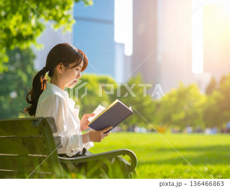 新緑の季節、都会のビル群、公園で読書をする女性 136466863