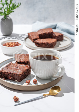 Pieces of chocolate brownie on a plate and a cup of espresso coffee on a light background Pieces of chocolate brownie on a plate and a cup of espresso coffee on a light background 136467405