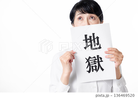 地獄と書かれた紙を持ち不安そうなシニア女性 地獄と書かれた紙を持ち不安そうなシニア女性 136469520