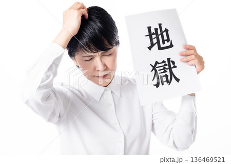 地獄と書かれた紙を持ち頭を抱えるシニア女性 136469521