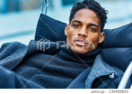 A man with dreadlocks laying on a chair 136469681