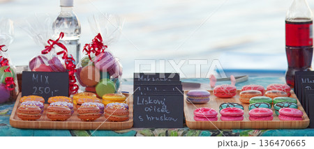 Colorful Macarons and Treats At Waterfront Market With Bottles, Gift Bags, And Chalkboard Signs 136470665