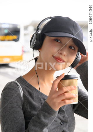ヘッドホンとコーヒーを持つ女性 ■撮影協力：関西国際空港（KIX） 136474546