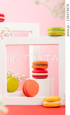 Colorful macarons arranged in white frames on a pink background with floral accents and vibrant colors Colorful macarons arranged in white frames on a pink background with floral accents and vibrant colors 136474678