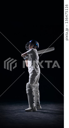Young cricket player standing with bat on shoulder in studio. Young cricket player standing with bat on shoulder in studio. 136475116