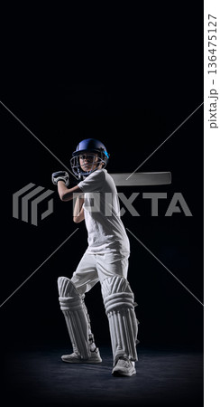 Young cricket player in batting stance on dark studio background. 136475127