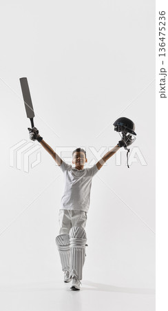 Happy young cricket player celebrating victory with bat and helmet on white. Happy young cricket player celebrating victory with bat and helmet on white. 136475236