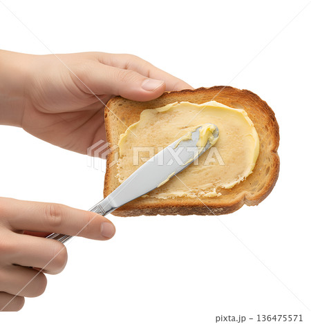 Hands spreading creamy butter over a warm, golden brown slice of toast, isolated. Perfect for breakfast concepts and comfort food Hands spreading creamy butter over a warm, golden brown slice of toast, isolated. Perfect for breakfast concepts and comfort food 136475571