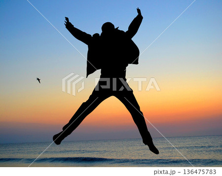 Boy silhouette jumping in the air, sunset sky Boy silhouette jumping in the air, sunset sky 136475783