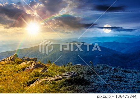 beautiful summer solstice landscape in mountains. day and night time change concept. stones on grassy alpine meadow with sun and moon. view from the edge of a hill. fluffy clouds on the sky 136475844