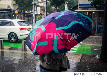 Pedestrians walk with umbrellas in the rain Pedestrians walk with umbrellas in the rain 136475875