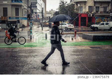 Pedestrians walk with umbrellas in the rain Pedestrians walk with umbrellas in the rain 136475879