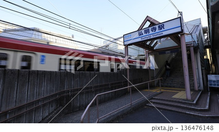 難読駅名で知られる京浜急行本線の弘明寺駅、2番出入口と走行中の電車 136476148