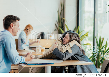 Coworkers embracing warmly during coffee break 136476421
