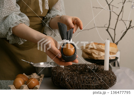 She carefully arranges dishes, lights candles, and paints eggs, filling the home with Easter spirit and cozy warmth. 136477795