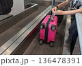A pink suitcase with a baggage tag attached at an airport check-in counter at Milano Malpensa Airport (MXP) 136478391