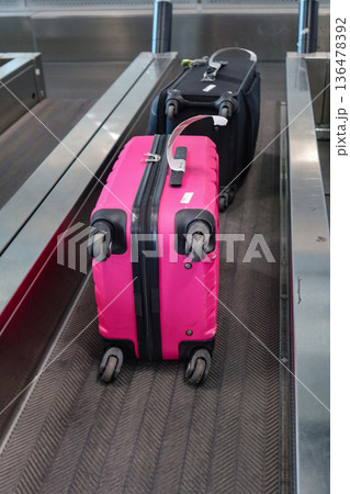 A pink suitcase with a baggage tag at an airport check-in counter at Milano Malpensa Airport (MXP) A pink suitcase with a baggage tag at an airport check-in counter at Milano Malpensa Airport (MXP) 136478392