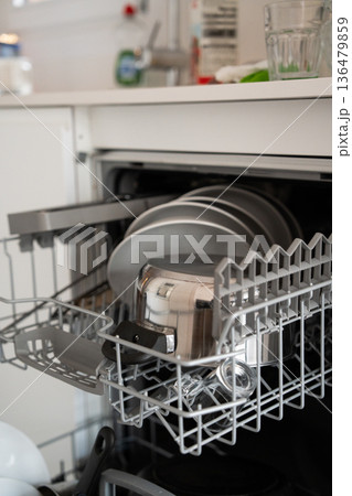 Dishwasher rack pulling out, full of kitchenware and clean dishes, illustrating modern home convenience, daily chores, and domestic efficiency 136479859