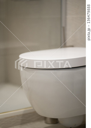 Modern wall-hung toilet offering a sleek design, ensuring a clean and hygienic environment in a domestic bathroom, representing comfort and elegant interior styling Modern wall-hung toilet offering a sleek design, ensuring a clean and hygienic environment in a domestic bathroom, representing comfort and elegant interior styling 136479888