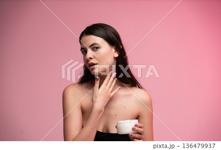 Young woman applying nourishing cream to her delicate neck and décolletage, prioritizing self-care and a healthy beauty routine for radiant, hydrated skin Young woman applying nourishing cream to her delicate neck and décolletage, prioritizing self-care and a healthy beauty routine for radiant, hydrated skin 136479937