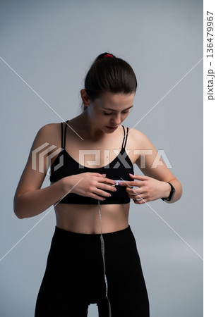 Young adult woman measuring bust size with a measuring tape, practicing self-care for body health, fitness, and weight loss progress, focusing on a healthy lifestyle Young adult woman measuring bust size with a measuring tape, practicing self-care for body health, fitness, and weight loss progress, focusing on a healthy lifestyle 136479967