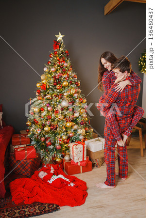 Couple celebrates holiday in front of Christmas tree Couple celebrates holiday in front of Christmas tree 136480437
