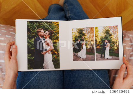Female hands flipping through a photo book with wedding photos 136480491