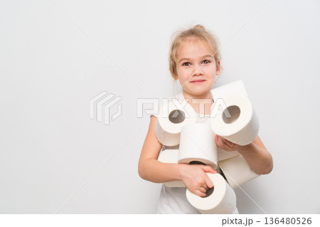 Child carries multiple rolls of toilet paper in a bright room Child carries multiple rolls of toilet paper in a bright room 136480526