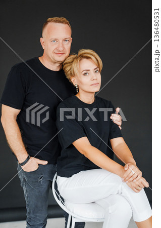 Couple posing for a portrait in a studio setting with dark background Couple posing for a portrait in a studio setting with dark background 136480531