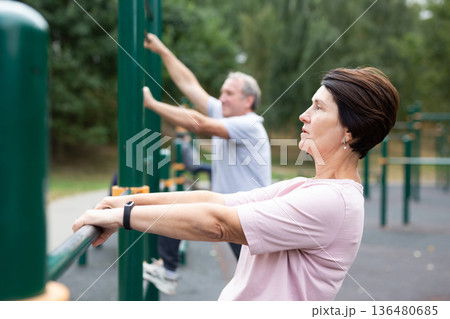 Healthy lifestyle in retirement - an elderly woman does a workout on the sports ground in park. Healthy lifestyle in retirement - an elderly woman does a workout on the sports ground in park. 136480685