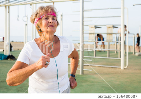elderly woman runs outside doing sports elderly woman runs outside doing sports 136480687