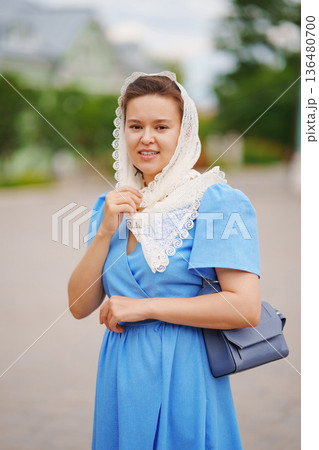 Woman in blue dress with scarf poses outdoors in spring Woman in blue dress with scarf poses outdoors in spring 136480700