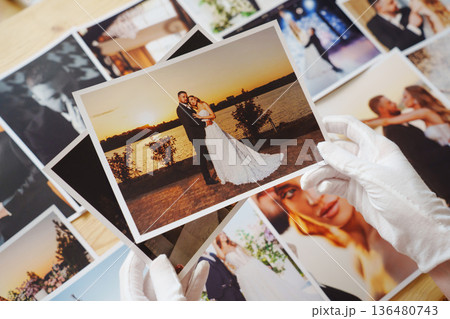 hands in white gloves and Beautiful printed wedding photos. 136480743