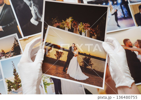 hands in white gloves and Beautiful printed wedding photos. 136480755