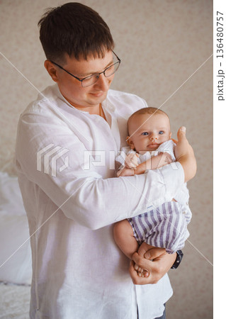 Father joyfully holding his baby in a bright room Father joyfully holding his baby in a bright room 136480757
