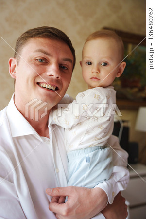 Father holding baby with a smile in a cozy room 136480762