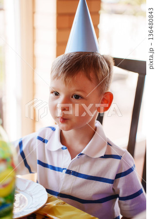 Child at table in party hat for birthday bash Child at table in party hat for birthday bash 136480843