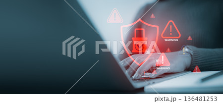Cybersecurity concept with user hands on laptop and red warning icons and digital shield protection for online data safety. 136481253