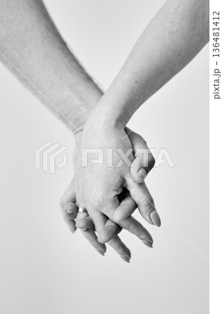 Two hands held together in grasp against neutral background. Close up of man's and woman's hand. Concept of intimacy, support, and trust. Black and white image. 136481412