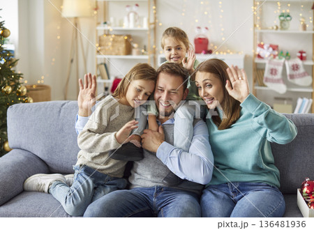 Happy family waving hands celebrating Christmas at home having online video call 136481936