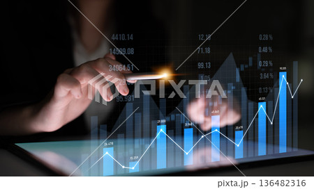 Business professional analyzing data trends on a digital tablet with graphs and statistics in a dark environment highlighting financial growth Scalp Business professional analyzing data trends on a digital tablet with graphs and statistics in a dark environment highlighting financial growth Scalp 136482316